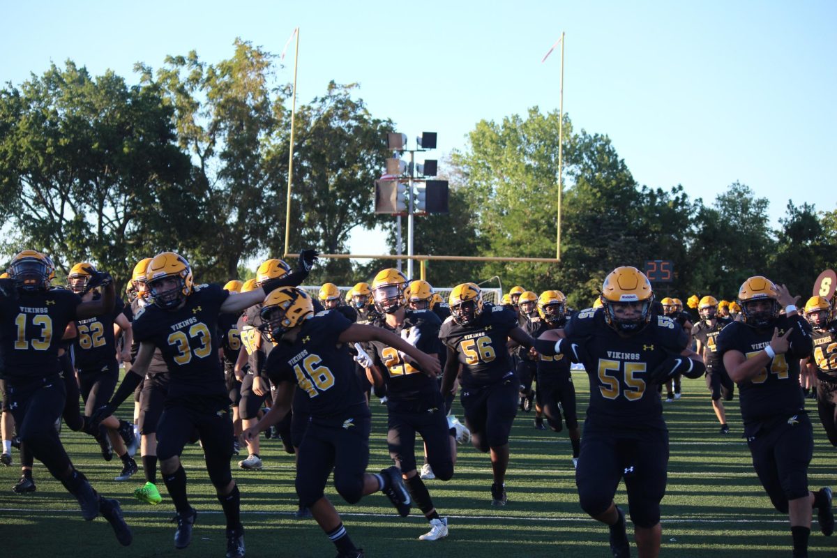 The boys varsity football team happily running onto the field for their first game of the season!