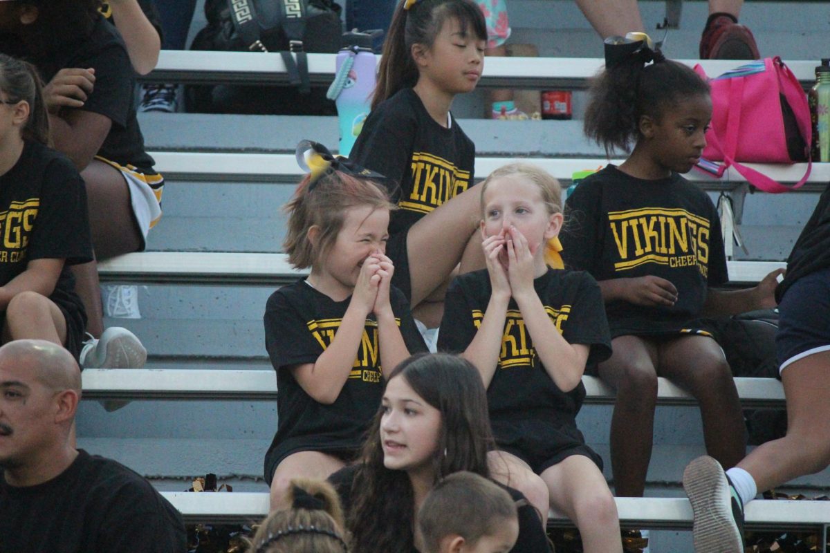 2 kids playing together as they wait to perform their cheer routine with the other cheerleaders.